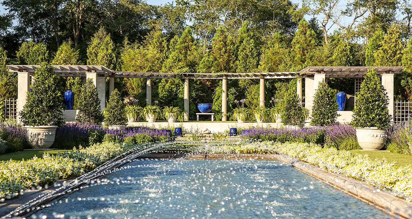An outdoor garden portico with reflecting pool and fountains